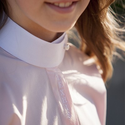 Criança com camisa branca de gola alta e texto bordado LEXHIS