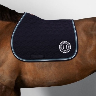 Tapete de sela azul escuro acolchoado com bordas azul claro e branco e logótipo HARCOUR em cavalo castanho.