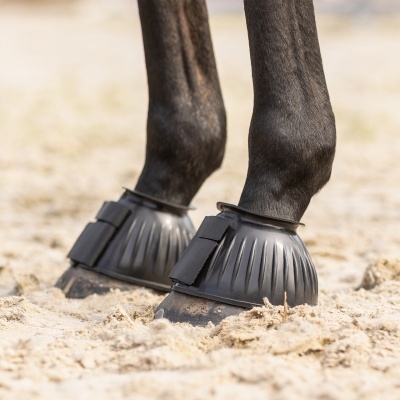 Patas de cavalo com botas de proteção pretas em areia
