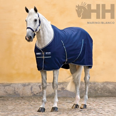 Cavalo branco com manta azul marinho e detalhes brancos posicionado ao ar livre