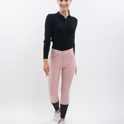Mulher com camisa preta de malha e calças rosa com bainhas pretas num fundo branco