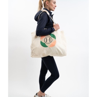 Mulher com roupa desportiva azul e bolsa de tecido bege com desenho circular e letra H