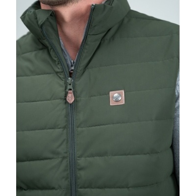 Colete acolchoado verde-escuro com fecho de correr e emblema quadrado castanho com botão metálico.