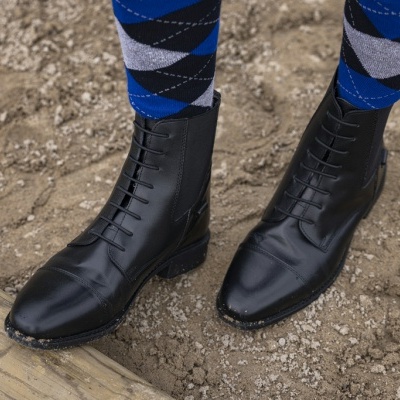 Botas pretas de couro com atacadores e meias azuis e cinzentas em areia