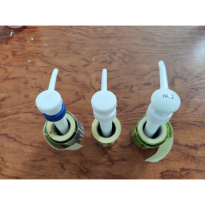 Três torneiras doseadoras brancas em garrafas, sobre mesa de madeira.