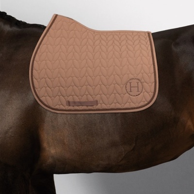 Capacho bege acolchoado para cavalo com padrão de folhas e letra H bordada.