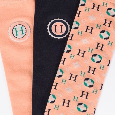 Três pares de meias compridas cor de pêssego e preta com emblema 'H' e padrão repetido em 'H'.