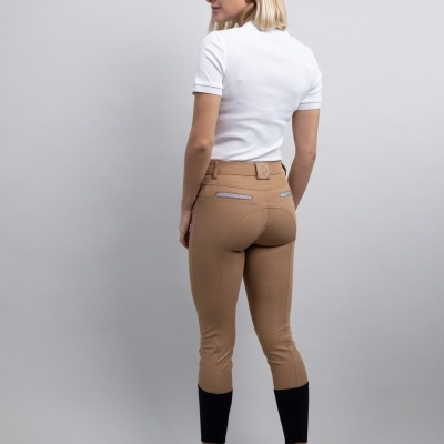 Mulher de costas com calças castanhas justas com detalhes pretos e camiseta branca