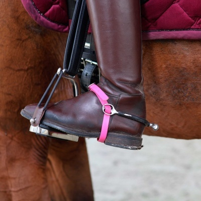 Bota de couro castanho em estribo com tira rosa em cavalo com manta vermelha