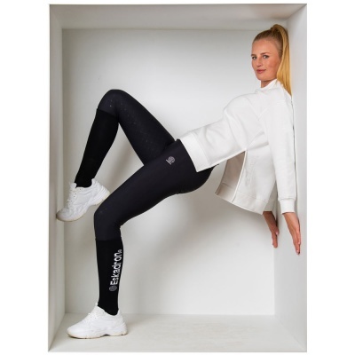 Mulher com leggings pretas e ténis brancos numa caixa branca