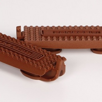 Dois tapetes castanho retangulares com textura irregular sobre uma superfície branca