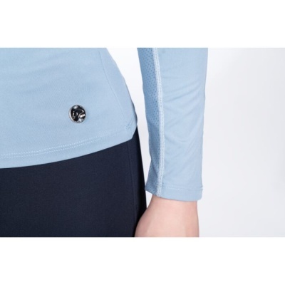 Detalhe de roupa azul clara manga comprida com símbolo metálico e calças escuras