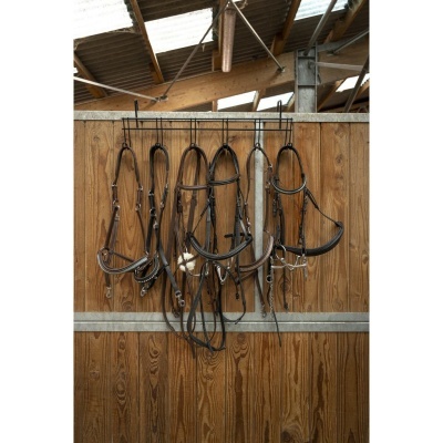 Cinco cabrestos de equitação pretos pendurados numa parede de madeira