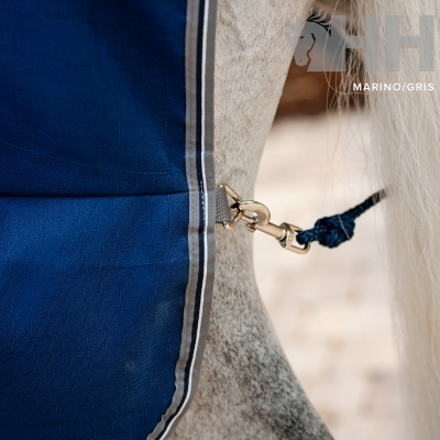 Capa azul marinho com risca branca e cinza presa ao pescoço de cavalo cinzento