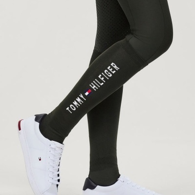 Leggings pretas com logo Tommy Hilfiger e sapatilhas brancas com detalhes em azul e vermelho.