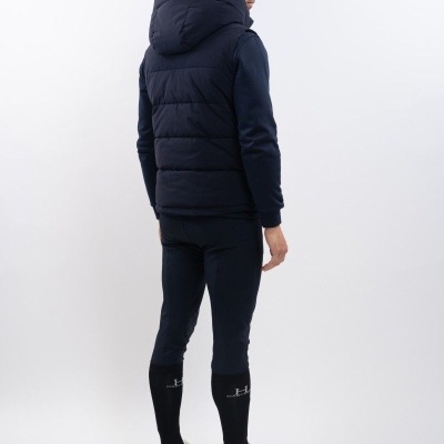 Homem de costas com colete acolchoado azul-marinho, calças justas azuis, meias pretas e sapatilhas brancas.