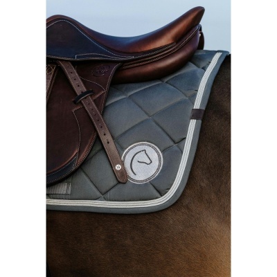 Sela de montar castanha sobre manta de sela cinzenta com logótipo circular em cavalo