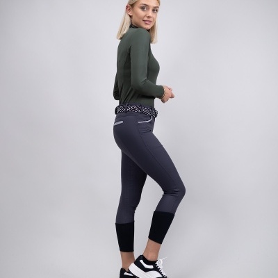 Mulher com camisola verde e calças de equitação cinzentas e ténis