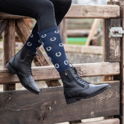 Botas de couro pretas com meias azuis estampadas sentado numa vedação de madeira