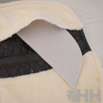 Manta bege com interior preto acolchoado numa superfície de madeira clara