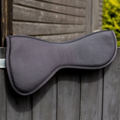 Almofada cinzenta para sela de cavalo sobre vedação de madeira cinzenta