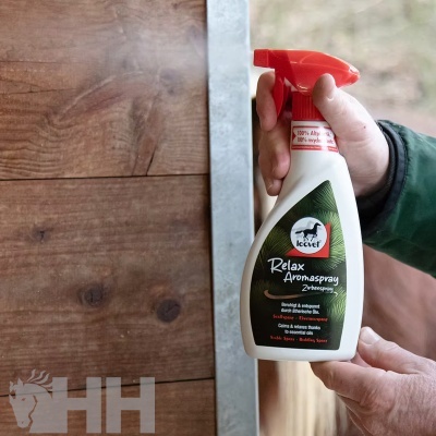 Frasco branco com pulverizador vermelho de Relax Aromaspray da marca EQUI junto a porta de madeira