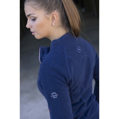 Mulher de perfil a usar casaco polar azul escuro com logos brancos