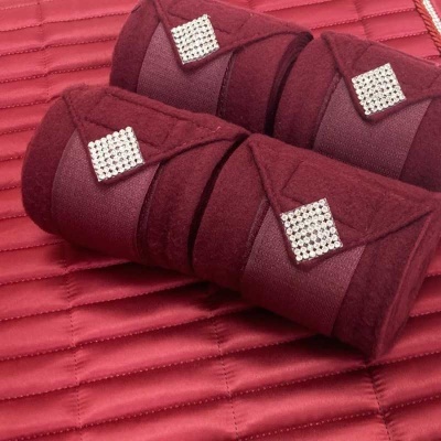 Rolos almofadados vermelhos com detalhe quadrado de strass sobre tecido vermelho acolchoado.