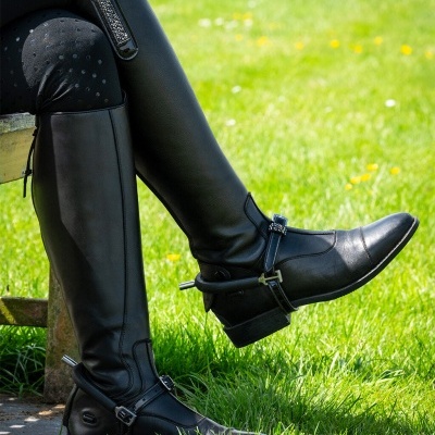 Botas pretas de pele altas com fivelas metálicas prateadas e detalhe decorativo brilhante ao ar livre