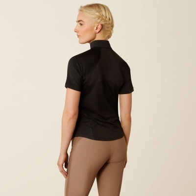 Mulher de costas com camisa preta de manga curta e calças castanhas claras