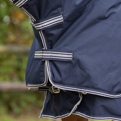 Cobertura azul escuro para cavalo com fitas azuis e brancas em ambiente externo