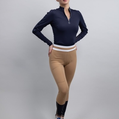 Mulher vestindo roupa desportiva com t-shirt azul escuro, calças bege e ténis brancos, em fundo cinzento