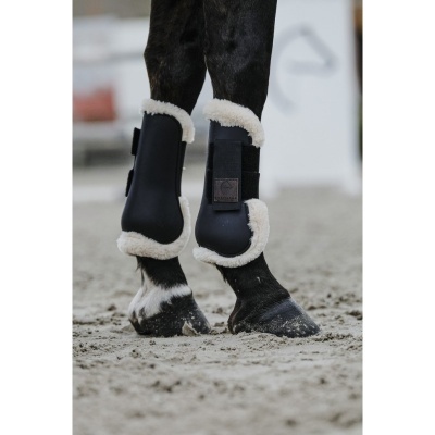Botas protetoras pretas para cavalo com pelo branco nas pernas traseiras de um cavalo