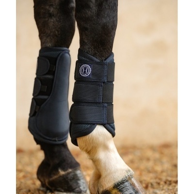 Proteções pretas para pernas de cavalo em piso de pedras