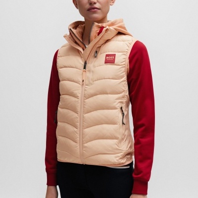 Colete acolchoado bege com capuz e logo BOSS usado por mulher com camisola vermelha