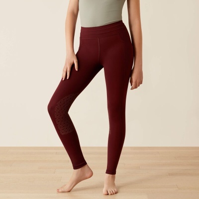 Mulher a usar leggings bordô com padrão texturizado no joelho em fundo neutro