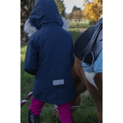 Criança de costas com parka azul e capuz com pêlo ao lado de cavalo com sela preta e manta azul