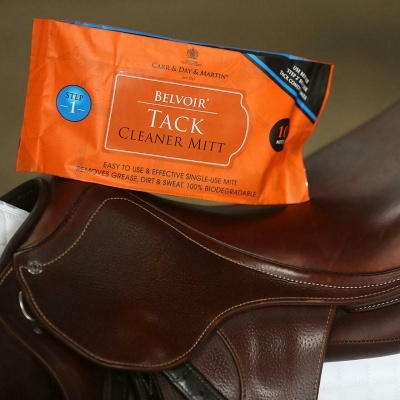 Pacote laranja do produto Belvoir Tack Cleaner Mitt colocado sobre sela de cavalo castanha