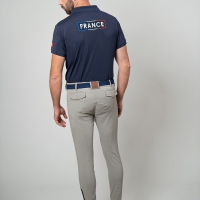 Homem de costas com polo azul escuro FRANCE, calças claras e sapatos desportivos