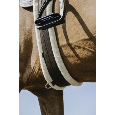 Cincha preta com bordas brancas peludas num cavalo castanho