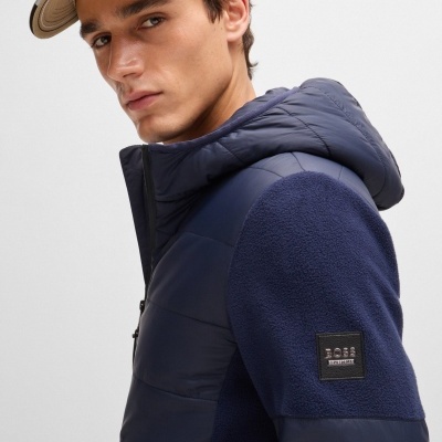 Homem com casaco azul escuro acolchoado e boné bege BOSS