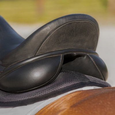Sela de cavalo preta de couro com suporte acolchoado preto sobre um cavalo castanho