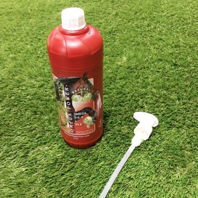 Garrafa vermelha de suplemento com rótulo colorido e dispensador branco sobre relva artificial