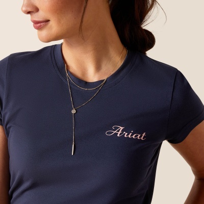 Mulher com t-shirt azul escura com logo Ariat e dois colares dourados