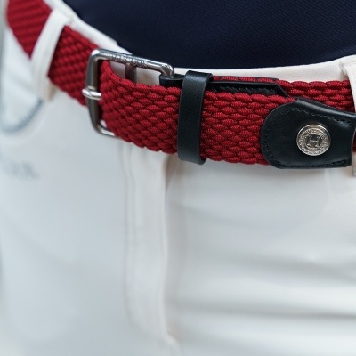 Cinto trançado vermelho com fivela metálica e calças brancas