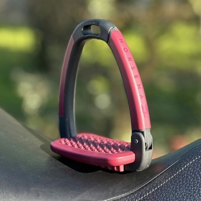 Estribo para equitação preto e vermelho com inscrição HORSEMAX sobre sela preta