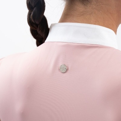 Pessoa de costas com camisa rosa claro, gola branca e emblema prateado redondo.