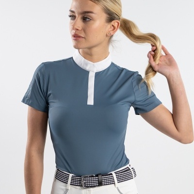 Mulher com t-shirt azul acinzentada e gola branca, calças brancas e cinto listrado