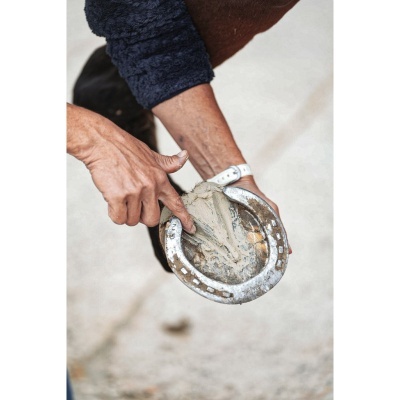 Mão segurando ferradura metálica com massa aplicada