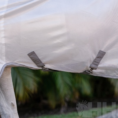 Toldo branco com tiras cinzentas e fivelas, fundo de vegetação verde